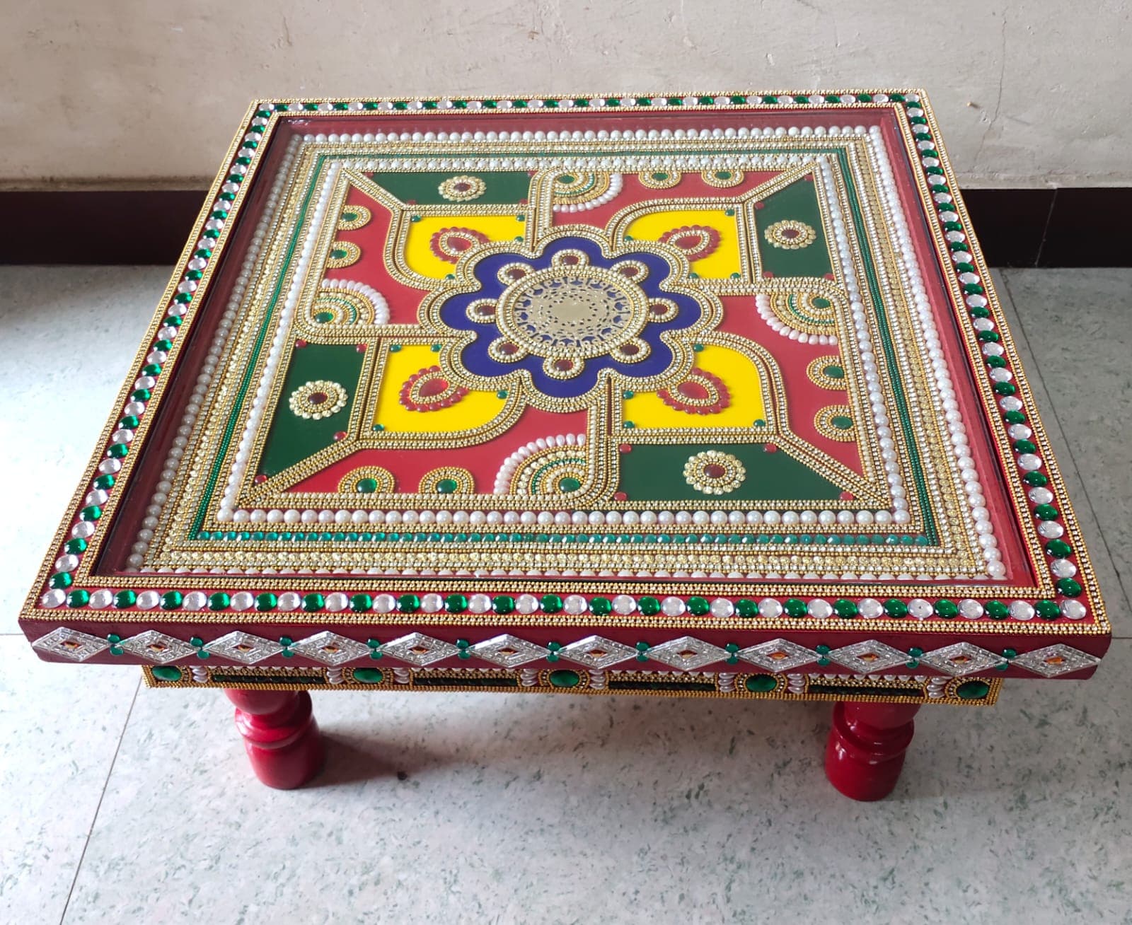 Handcrafted wooden pooja chowki with mandala design, emerald stone border and pearl accents