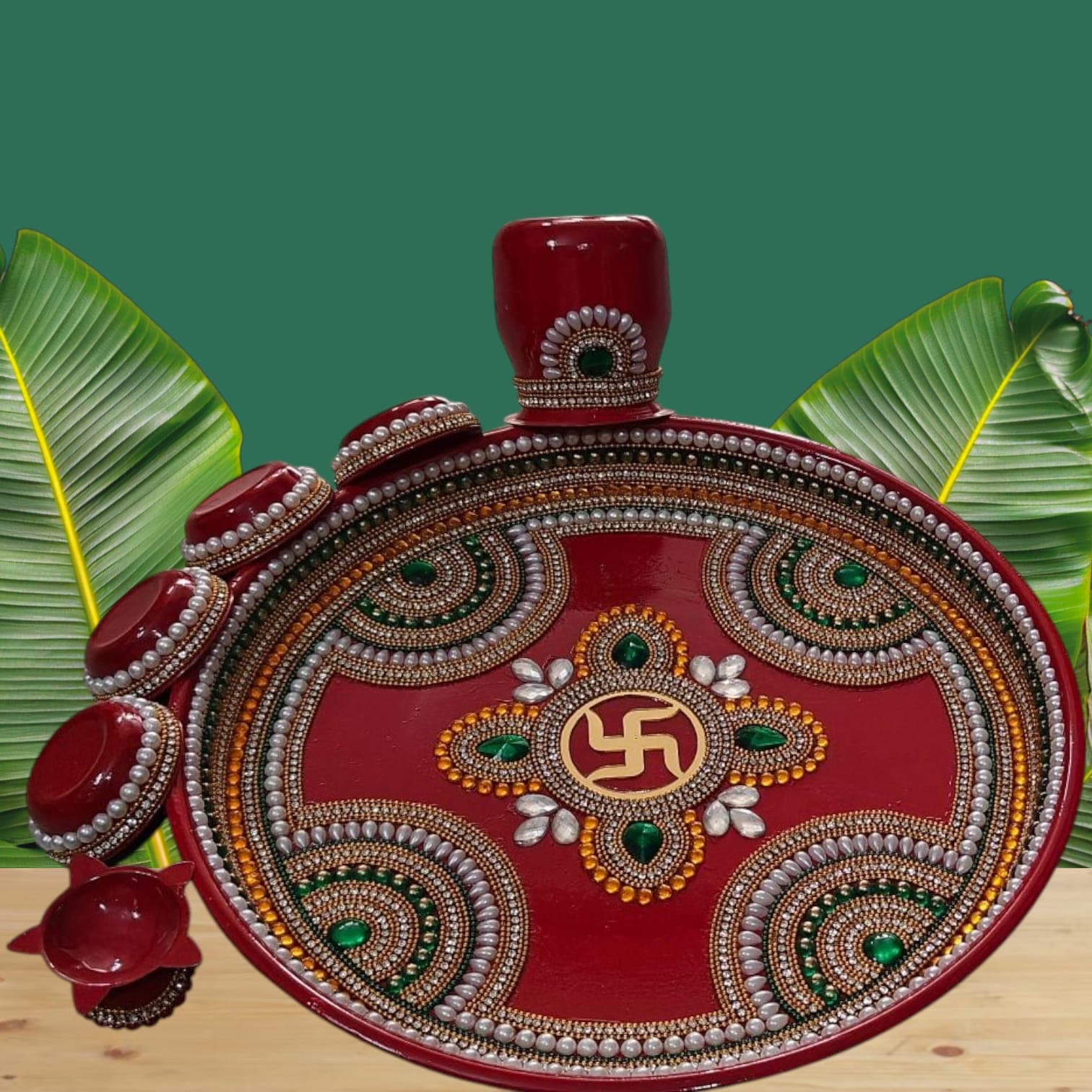 Deep maroon handcrafted pooja thali with kundan swastik motif and pearl embellishments by Priti's Craft